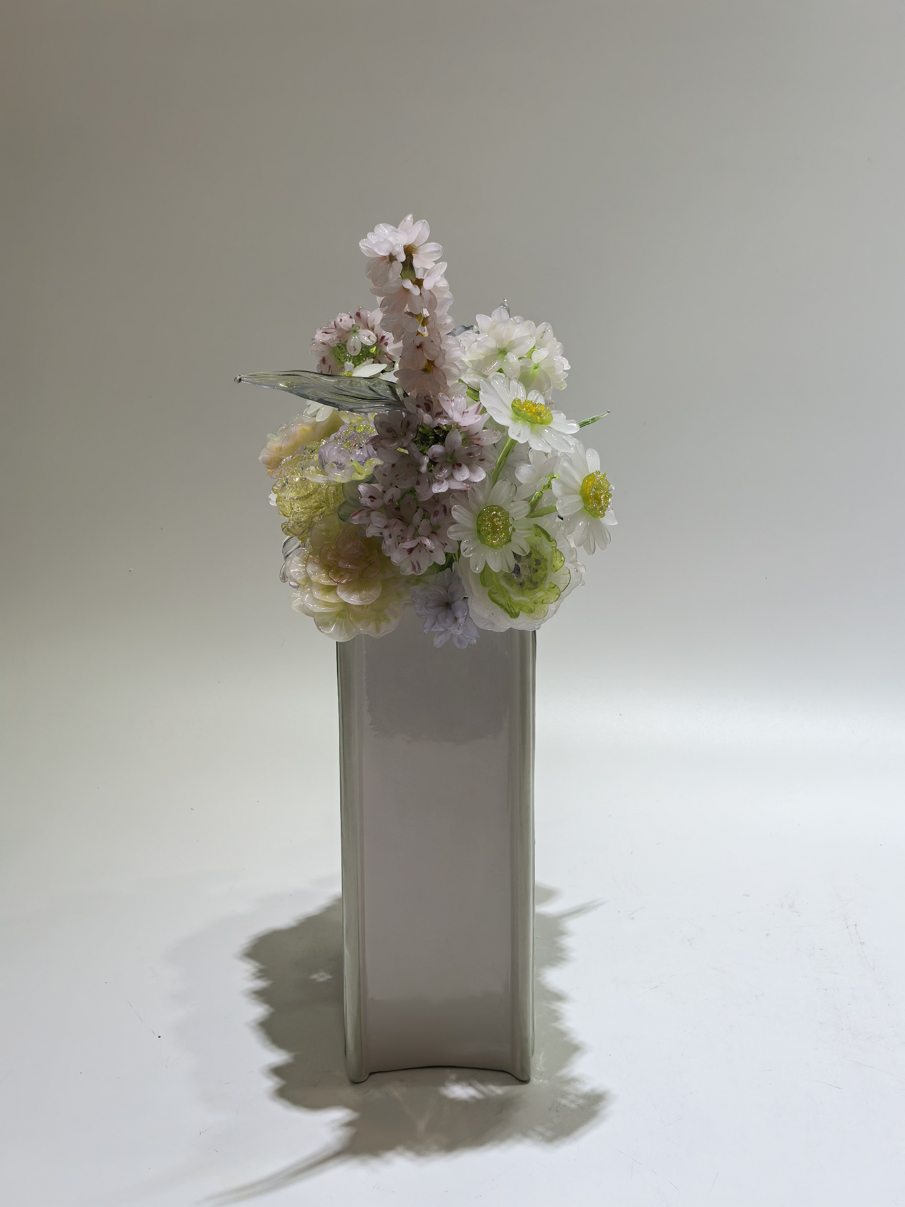 Mixed handmade glass flowers in a green book-shaped vase